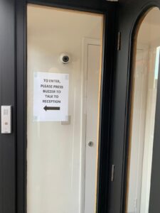 Front door notice asking visitors to press the buzzer for reception