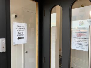 Front door notice asking visitors to press the buzzer for reception